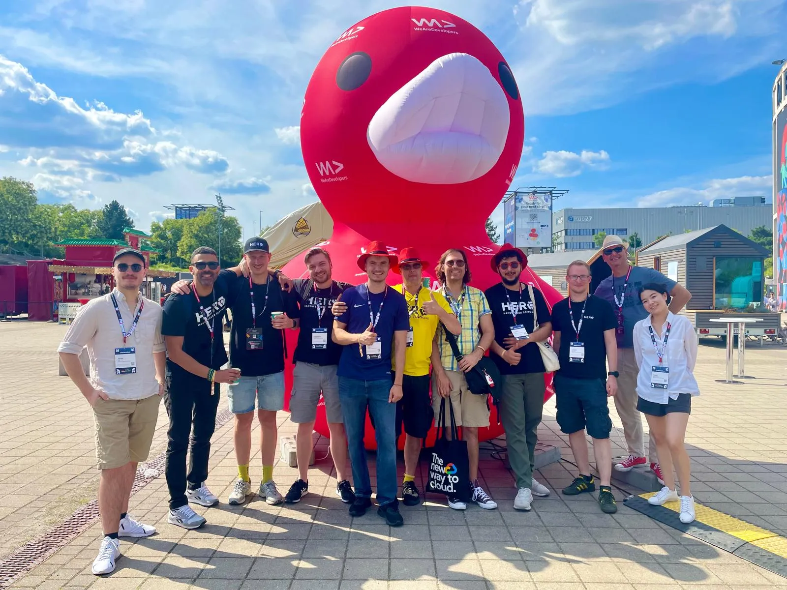 A group of eleven people in font of a large red inflated duck